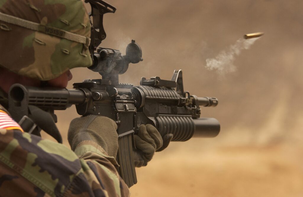 A soldier is holding his rifle and aiming it.